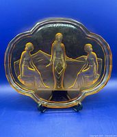 Full view of amber glass dresser tray on stand showing overall shape and relief design