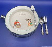 Top view of ceramic baby bowl with utensils laid beside