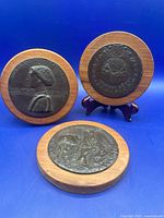 Group view of the three bronze medallions on wood mounts