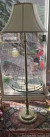 Full view of brass floor lamp with shade and glass table