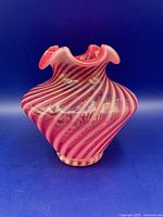 Three-quarter view showing cranberry opalescent spiral stripes and ruffled rim