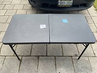 Top view of the black plastic folding table showing two rectangular sections flat and connected.