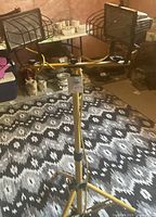 Work light on yellow tripod stand showing two rectangular light heads with wire cages around bulbs.