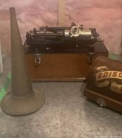 Phonograph mechanism, horn and curved cover displayed together