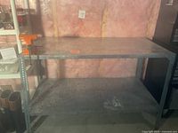 Front view of the metal workbench with bench vise on left side showing general condition and provides size context.