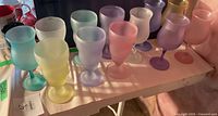 Set of 12 frosted pastel colored glasses arranged in a row showing different colors including blue, yellow, pink, purple, and white.