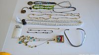 Overview of various costume jewelry pieces including multiple necklaces, a brooch, a painted pendant, and a hammered metal choker.