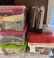 Photo of three plastic storage containers stacked containing fabrics and sewing patterns.