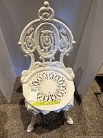 Front view of small white cast iron garden chair showing full chair height and detailed backrest design.