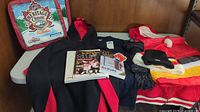 Hoodies, t-shirts, hats, scarf, and hockey books arranged on table.