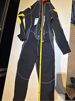 Full view of the wetsuit laid flat with measuring tape showing length.