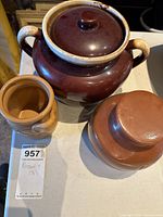 Photo of three pottery pieces showing two with lids and one without on a white surface with MaxSold tag.