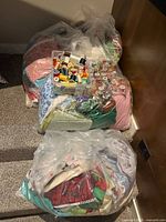 Four large clear plastic bags filled with assorted quilting and sewing fabric pieces in various colors and patterns, with a clear plastic organizer on top containing multiple thread spools.