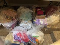 Overview of six plastic bags containing assorted quilting fabric scraps and one box of pre-cut squares