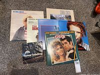 Photo showing seven vinyl record albums laid out on carpet, includes Grease, Rachel Sweet Fool Around, Chalk Circle Mending Wall, Lunar Landing Man on the Moon, The Big Chill soundtrack, Simply Red Women