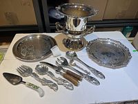 Full lot view showing EP brass ice bucket, two EP copper platters, metal serving utensils, and napkin rings on white surface.