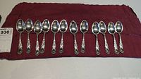 Eight teaspoons laid out on burgundy cloth
