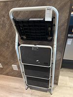 Folded 3 step ladder showing the back side with metal frame and black step surfaces.