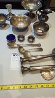 Overall view of twelve sterling silver pieces including bowls, spoons, candlesticks, creamer, and condiment dishes on white surface