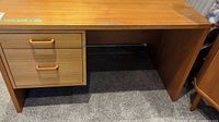 Front view of teak wood office desk showing two drawers on left side and open leg space on right side.