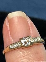 Close-up of ring on finger showing central diamond and accent stones