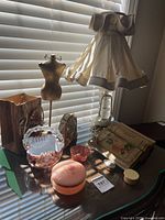 Overview of all items on tabletop including lamp, mannequin, glass bowls, boxes, book, plaque