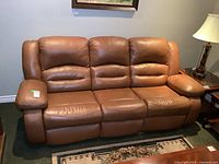 Front view of brown leather three-seat recliner sofa