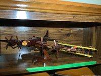 Dark brown four-engine plane on stand with yellow biplane behind