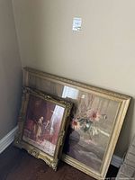 Both framed paintings leaning against wall, showing overall size difference