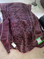 Folded Persian rug on floor showing overall geometric pattern and colour