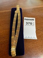 Full view of gold collar necklace on display pad