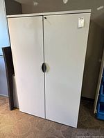Full view of light gray metal storage cabinet with two doors and keyed lock