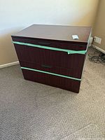 Front view of dark woodgrain two-drawer lateral file cabinet with black handles and lock
