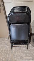 stack of six black metal folding chairs folded
