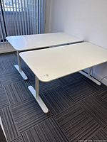 Two matching white IKEA Bekant desks side by side