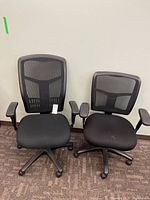 Two black mesh office chairs front view
