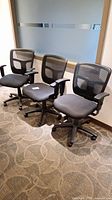 Three black mesh-back office chairs aligned