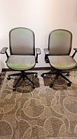 Front view of both mesh office chairs showing seats, backs, arms, and caster bases