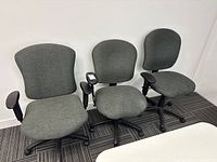 Three gray fabric office chairs side by side on carpet