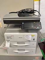 Front view of Ricoh Aficio MP 301SPF with control panel, drawers and cables