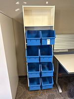 Full view of white shelf unit with eight blue bins