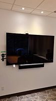 Front view of wall-mounted Samsung 75" TV with camera and soundbar