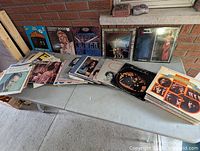 Wide view of table with stacks of vinyl records and several upright jackets visible