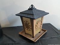 Full view of bird feeder showing shape, roof, tray, and hanging loop