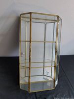 full view of glass and brass display cabinet standing upright
