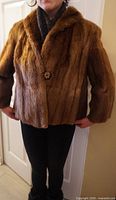 Front view of brown fur short coat worn on model, showing single button and shawl collar