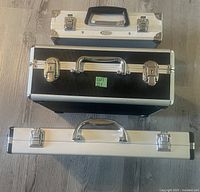 Top view of the three aluminum cases in black and silver, showing their relative sizes and latches.