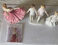 Three Royal Doulton figurines displayed on a surface, showing the figures and included information pamphlet