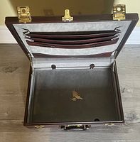 Open brown briefcase showing interior compartments and keys inside.