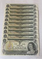 Ten crisp Canadian one dollar bills dated 1973 laid out to show sequential serial numbers.
